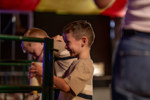 A boy with a huge smile on his face whilst he bottle feeds a lamb.