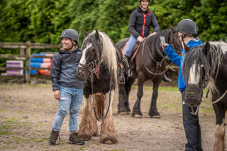 An image of a man posing with a horse whilst his mate takes a photo.