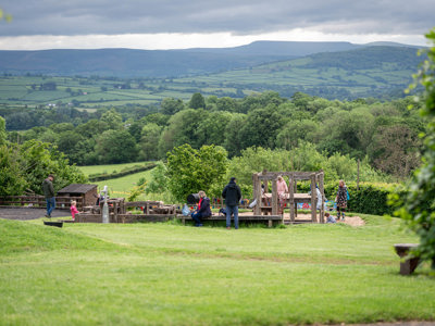 A landscape wide shot of the sand and water outdoor play area at Cantref Adventure Farm, with a lovely view behind.