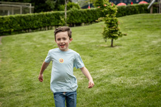 An image of an excited boy running over grass towards the outdoor adventure play area at Cantref Adventure Farm.